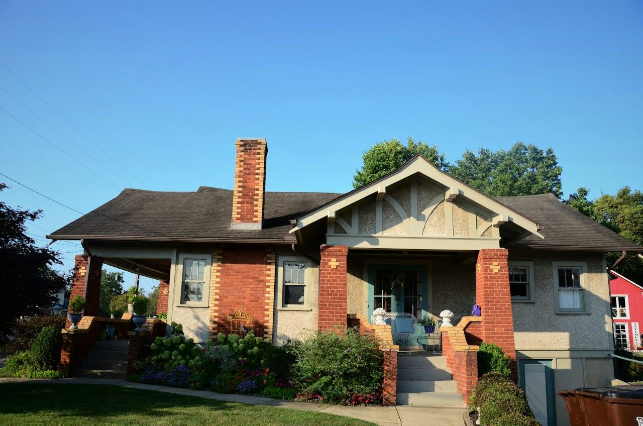 A Craftsman bungalow with a front-gabled porch, brick piers and a brick chimney under a deep, overhanging roof