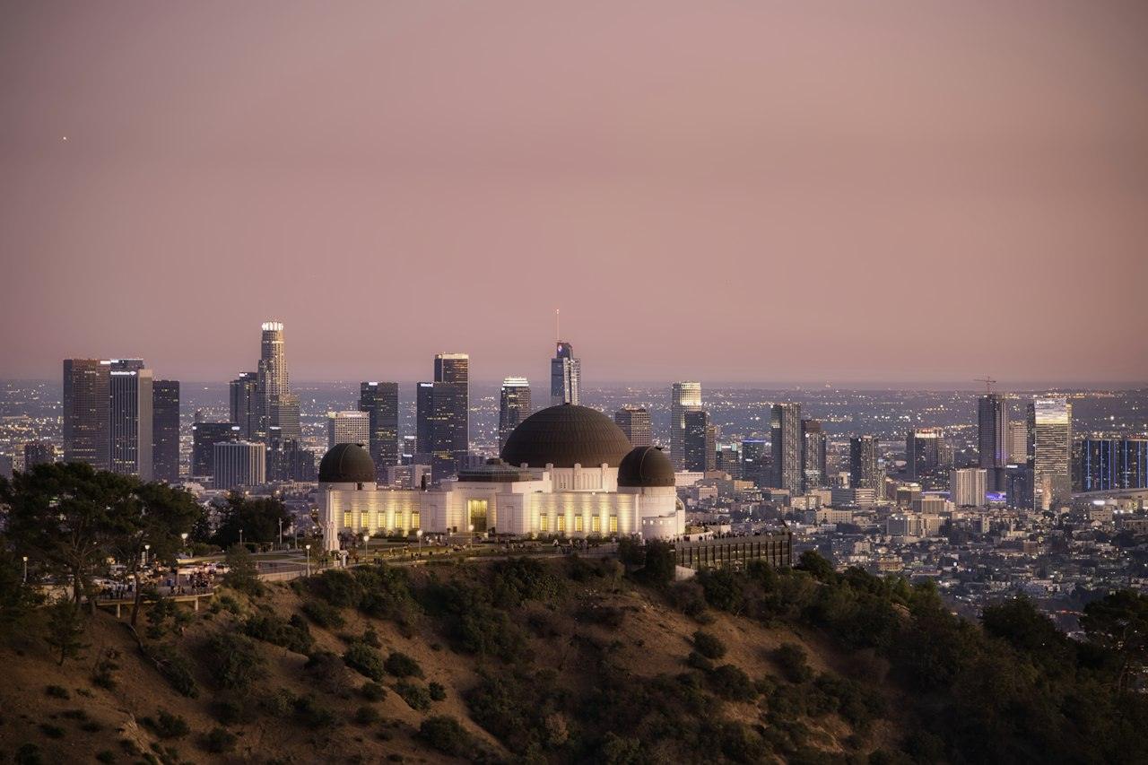 Griffith Observatory at sunset with the Downtown Los Angeles skyline behind it